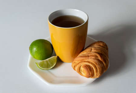 yellow cup with traditional hot drink, lemon, one bread and white background.の写真素材