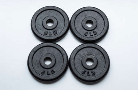 Closeup to a four dumbbell disc of 5 pounds over white background. Ideal for fitness, sports, and healthy life.の写真素材