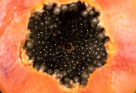 Macro photography to asliced orange fresh papaya with seeds inside. Fruit and texture conceptの写真素材
