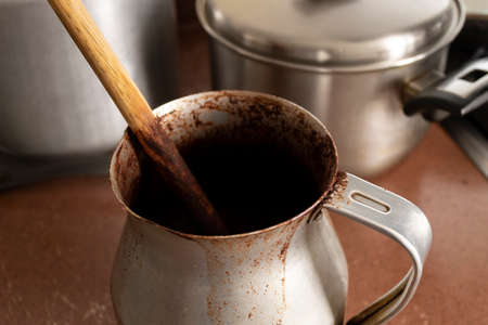 Close up to an old dirty cocoa cooking pot over kitchen furniture with others cooking pots at background. Traditional Kitchen conceptの写真素材