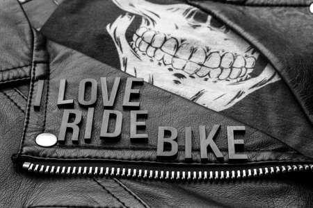 closeup to I love ride bike lettering over biker leather jacket and skull kerchief. motorcycle style. Black and white photographyの写真素材