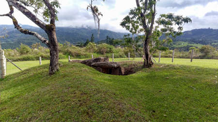 An ancient mound dolmen. Monolithic tomb formed with volcanic rocks into grass at Colombian San Agustin archaeological park. antique pre columbus culture.の写真素材
