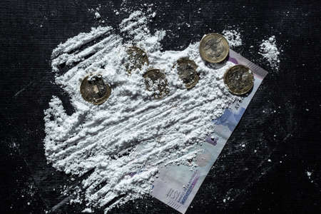 Closeup to a cocaine lines, colombian coins, colombian money paper and a blue credid card over a black background. Drugs and addiction conceptの写真素材