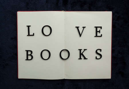Close up to LOVE BOOKS lettering over blank notebook at blue navy background. Reading and study concept photographyの写真素材