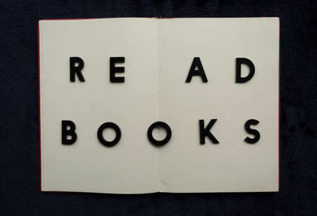 Close up to READ BOOKS lettering over blank notebook at blue navy background. Reading and study concept photographyの写真素材