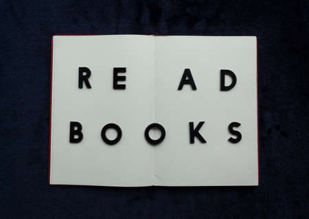 Close up to READ BOOKS lettering over blank notebook at blue navy background. Reading and study concept photographyの写真素材