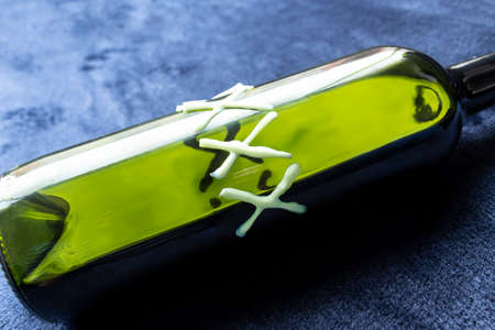 Close up to a home made liquor inside a green bottle over blue background. Party and liquor conceptの写真素材