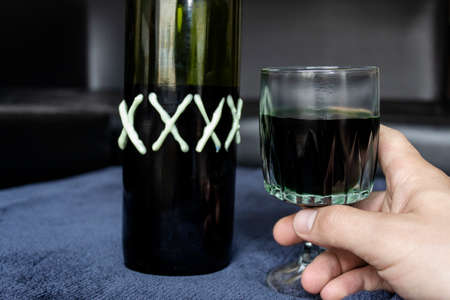 Close up to a man holding a cup of green homemade liquor with green artesanal alcohol bottle. Party and liquor conceptの写真素材