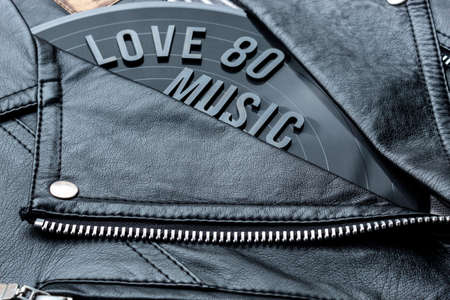 Closeup to a love 80 music lettering art over a black leather biker jacket with LP vinyl disc. Music lover concept, retro photography.の写真素材