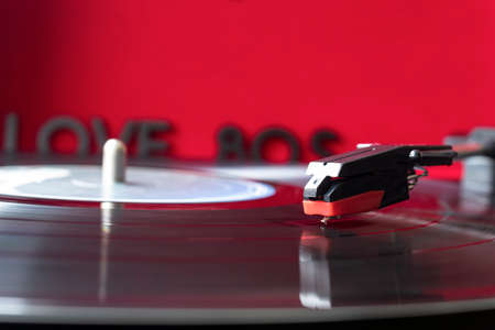 close up to a turn table needle playing a LP vinyl disc with turn table and I love 80s lettering...