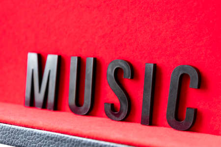 Closeup to a MUSIC black lettering word over a red background. Music lover conceptの写真素材