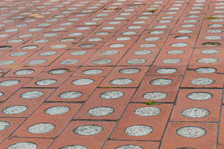 Closeup to a red orange brick floor texture with concrete and small grass.の写真素材