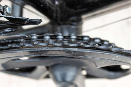 Closeup to an old black bicycle chain ring with oiled chain and front derailleur.の写真素材
