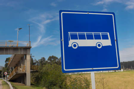 Blue bus station traffic signal in countrifield with a pedestrian brige at background and blue sky