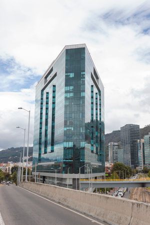 BOGOTA, COLOMBIA - A modern triangular skyscraper wityh blue window reflection blue cloudy sky at north city business districtのeditorial素材