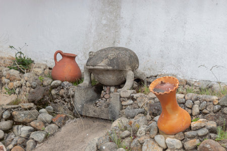 GUATAVITA, COLOMBIA - A small concrete frog sculpture in a dry fount with two red ceramic pots in middle of townのeditorial素材