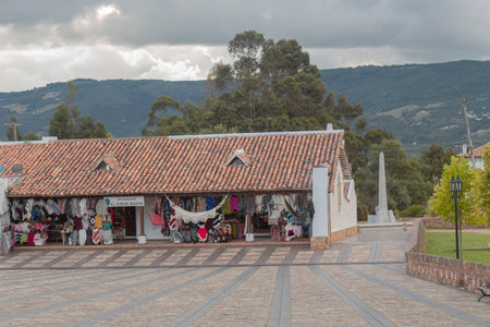 GUATAVITA, COLOMBIA - Guatavita gift shops with colonial architecture located in main square with andean mountains at background in afternoon cloudy dayのeditorial素材