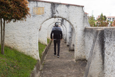 GUATAVITA, COLOMBIA A young man walkinf inside an old arc colonial pedestrian street at South American town. Travel and adventure conceptのeditorial素材