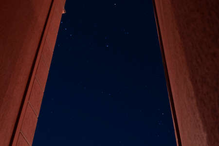 A beautiful shot of starry city night sky in middle of two red walls with orion constellation. Astronomy and science conceptの写真素材
