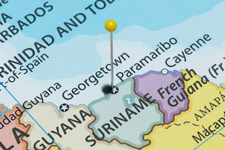 Close up to a Paramaribo city with a yellow pin needle into Suriname country political mapの写真素材