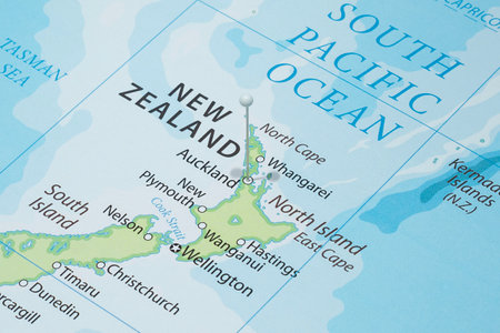 Close up to an Auckland city with a white pin needle into New Zealand country political mapの写真素材