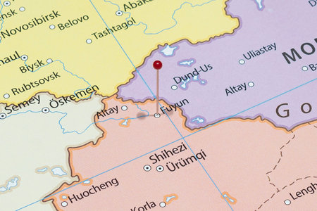 Close up to a Fuyun city with a red pin needle into China country political mapの写真素材