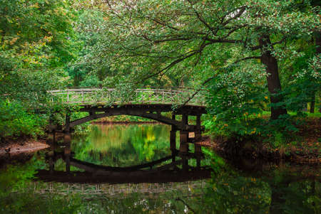 A wooden bridge over a pond in the autumn parkの写真素材