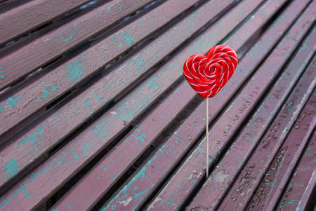 Red lollipop heart shaped on the bench in parkの写真素材