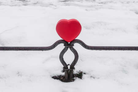 Red box heart shaped on fence in winter parkの写真素材
