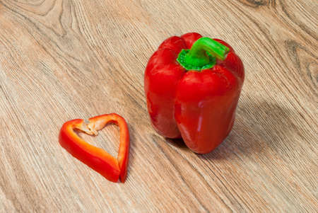 Pepper and its heart shaped slice on a wooden backgroundの写真素材