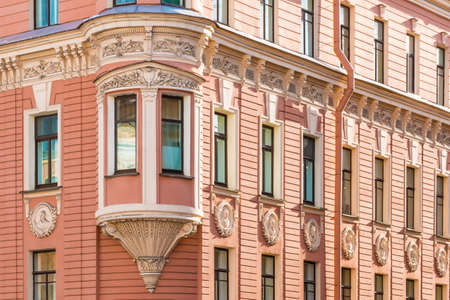 Many windows in row and bay window on corner of facade of urban apartment building angle view, St. Petersburg, Russiaの写真素材