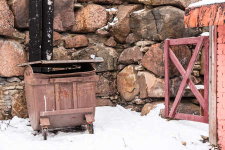 Garbage container and wicket near a stone wall in winter sceneの写真素材