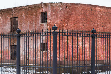Wrought iron fence at the background of the brick facade of an abandoned buildingの写真素材