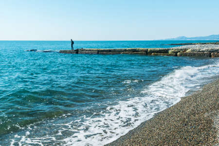 Breakwater with a silhouette of the person and pebble beach with sea viewsの写真素材