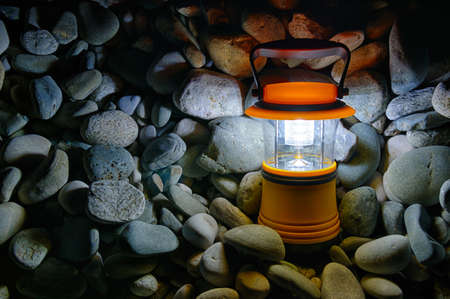 Luminous hand lantern standing on a pile of pebble, HDR processing