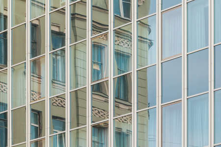 Specular facade of office building with reflection of an old building facadeの写真素材