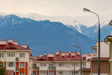 View of snowy mountains from the residential district on overcast dayの写真素材