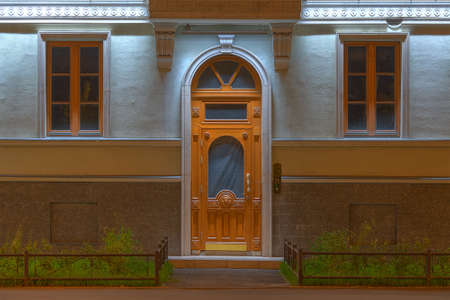 Two windows and door in a row on night illuminated facade of urban apartment building front view, St. Petersburg, Russiaの写真素材