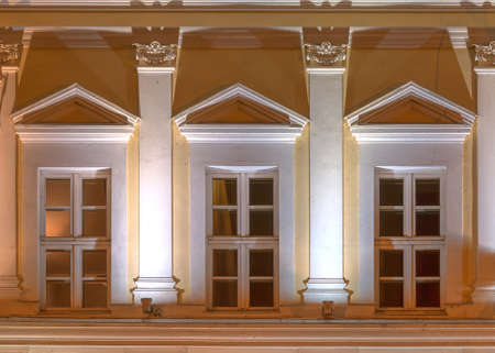 Three windows in a row on night illuminated facade of urban office building front view, St....