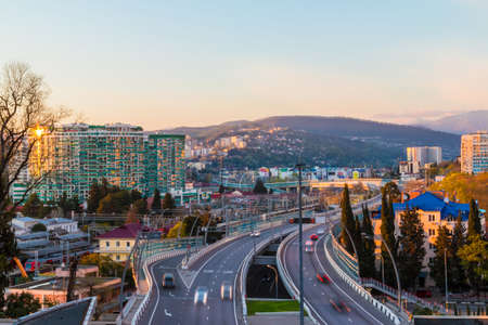 Aerial view of city, mountains and highway Doubler of Kurortnyy Prospekt at sunset, Sochi, Russia