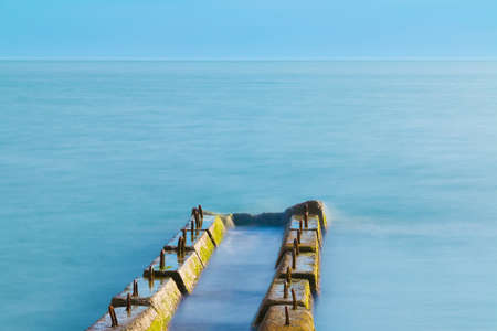 Long exposure view of the concrete mole in the sea and horizon far away in sunny dayの写真素材