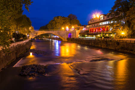 Night view of illuminated Rivyerskiy bridge and Sochi river with embankment, Sochi, Russia