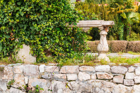 Dilapidated stone fortress wall with bushes in the old park close-upの写真素材