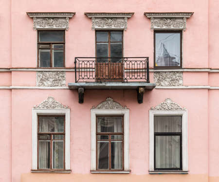 Several windows in a row and balcony on facade of urban apartment building front view, St....