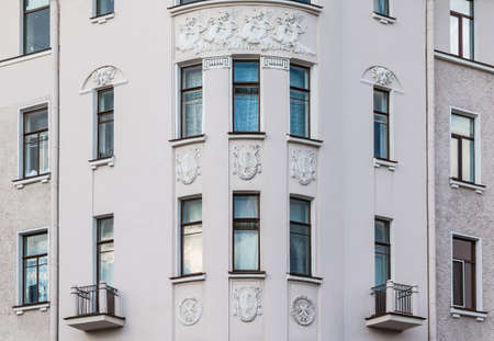 Several windows in a row and balconies on corner of facade of urban apartment building front view, St. Petersburg, Russiaの写真素材