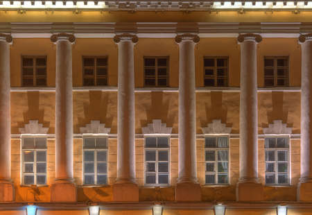 Several windows and columns in a row on night illuminated facade of Naval Academy front view, St....