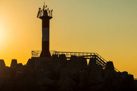 Low-key photo of the lighthouse on the northern mole of Sochi at sunset, Russiaの写真素材