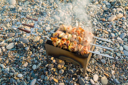 High-angle shot of shashlik fried on a mangal on the pebble beachの写真素材