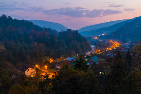 Landscape of illuminated Plastunka village in the valley and mountains in autumn twilight, Sochi,...