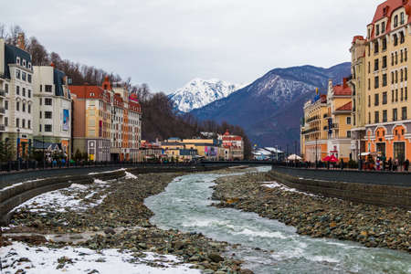 Krasnaya Polyana, Sochi, Russia - January 4, 2018: Winter landscape of the embankment, apartment buildings and Mzymta River on the background of mountainsのeditorial素材